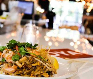 A plate of Pad Thai with shrimp on bar dining table